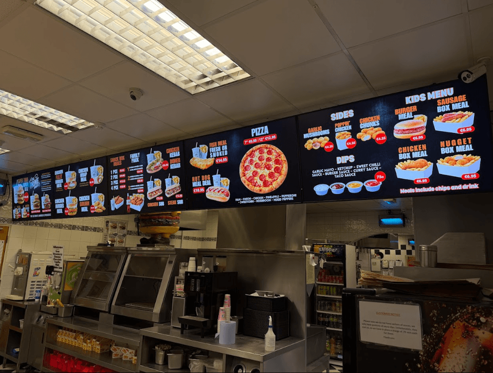 Five digital menu boards installed above a takeaway counter